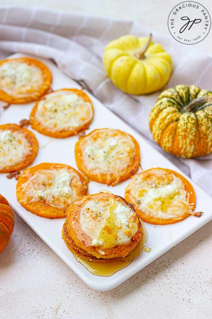 Squash lined up on a white serving platter.