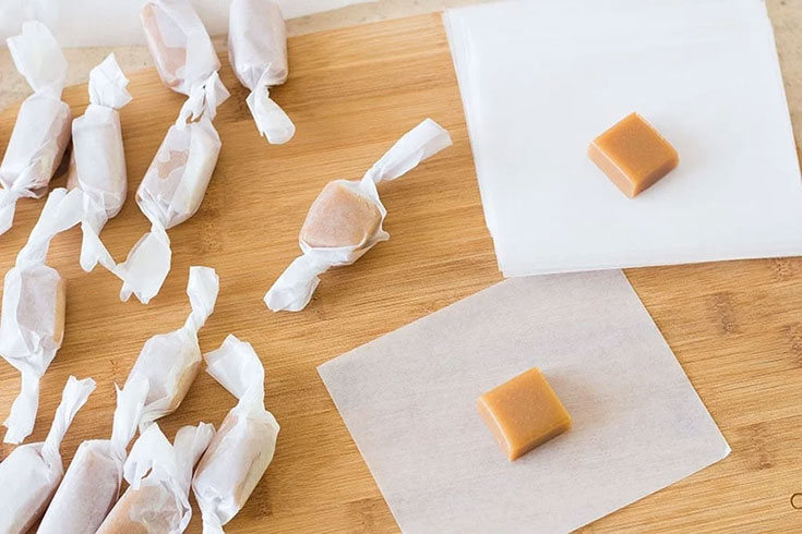 Individual soft caramels on a cutting board.