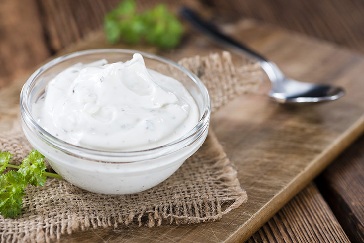 A small glass bowl filled with herbed sour cream.