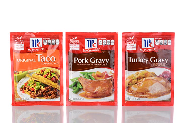 Three spice packets on a white background. Taco seasoning, pork gravy mix and turkey gravy mix.