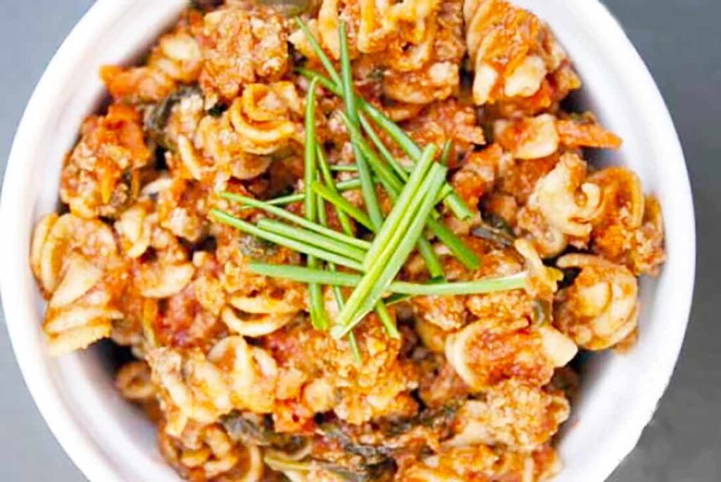 A white bowl filled with Superfood Rotini and garnished with fresh, green chives.