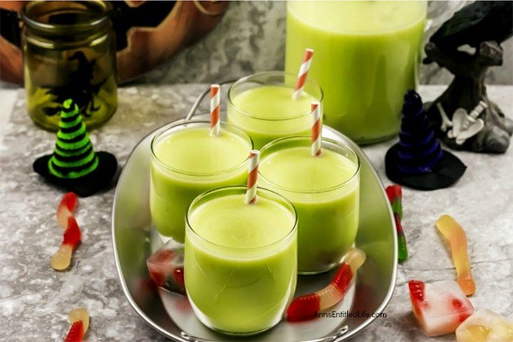 Swamp water punch in four glasses with straws, sitting on a tray.