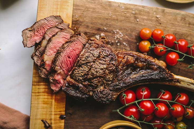 An overhead view of a partially sliced tomahawk stead on a cutting board.