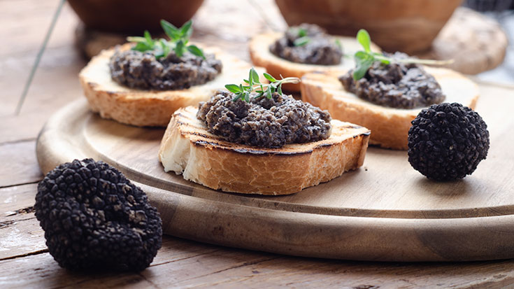 Slices of french baguette covered in truffle mushroom spread.
