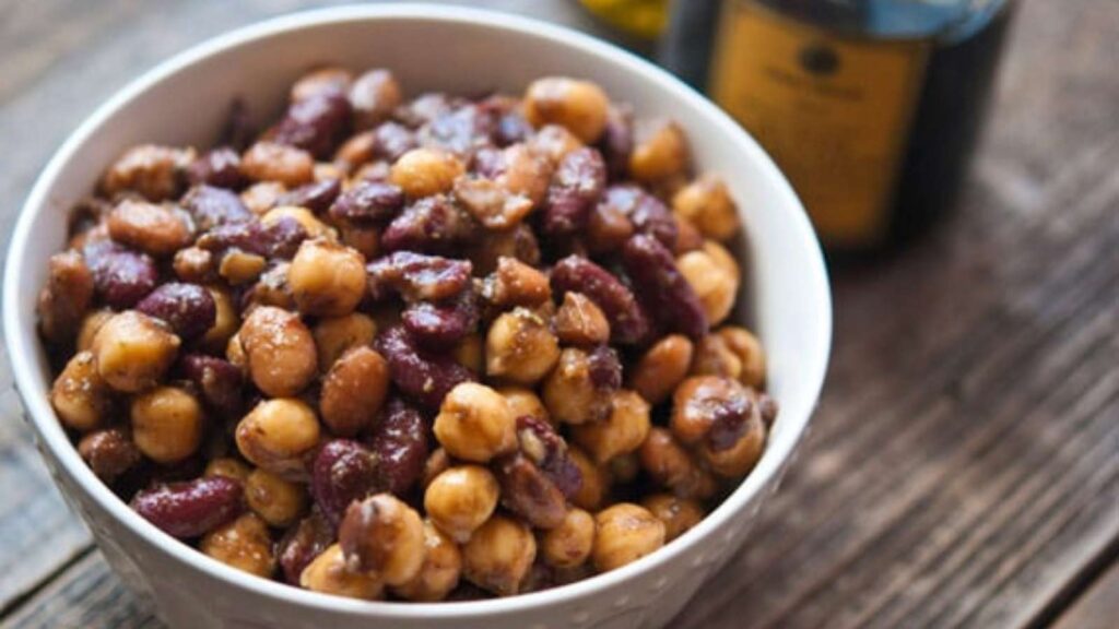 A white bowl filled with 3 bean salad sits on a wooden table.