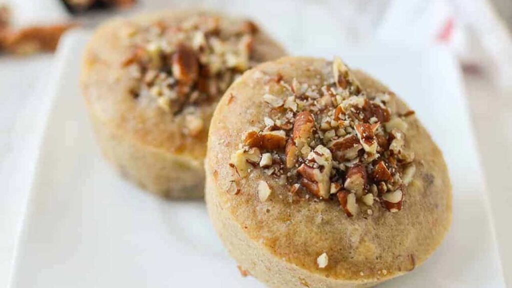 Two banana pecan muffins on a white plate.