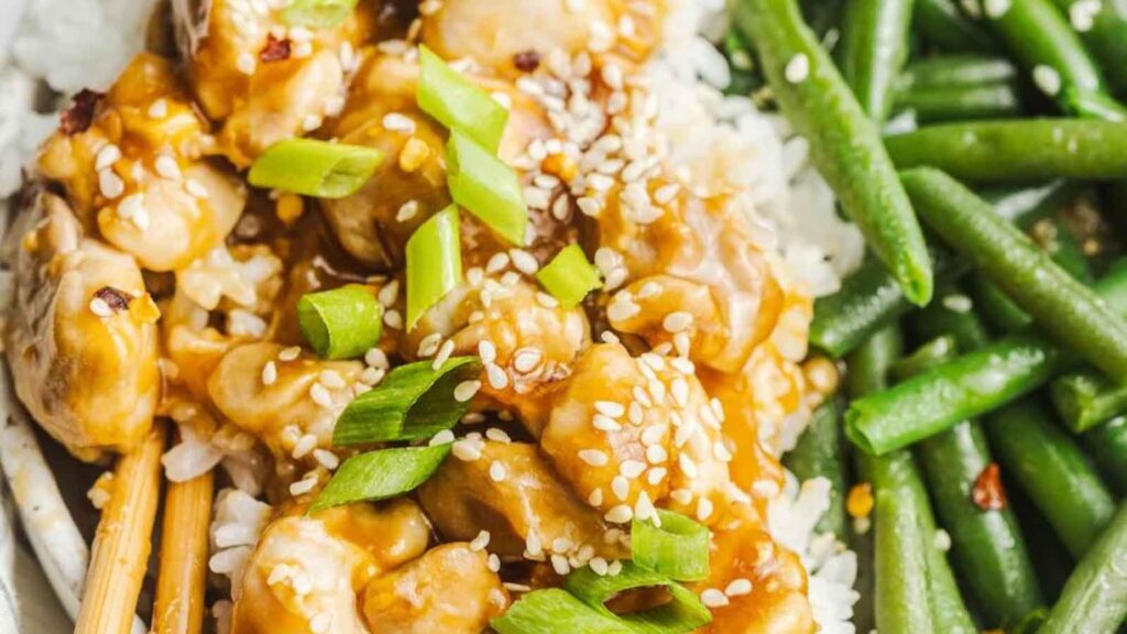 A closeup of chicken teriyaki stir fry with rice and green beans on the side.