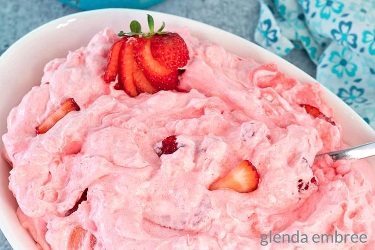 A white casserole dish filled with cottage cheese salad and garnished with fresh strawberries.