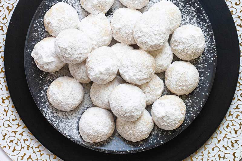 A platter filled with snowball cookies dusted with powdered sugar.