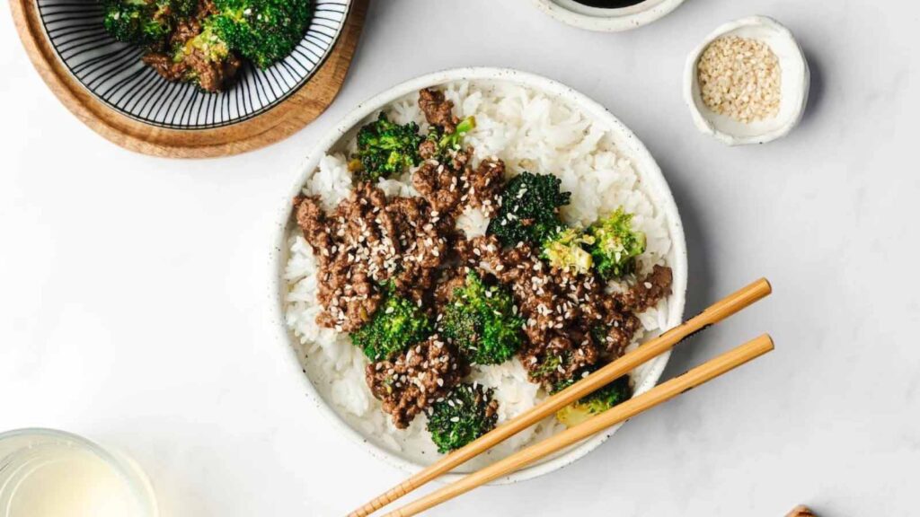 An overhead view of ground beef and broccoli stir fry over rice on a white plate.
