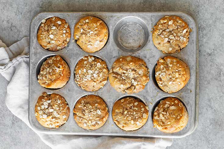 An overhead view of a muffin pan filled with honey pear muffings.