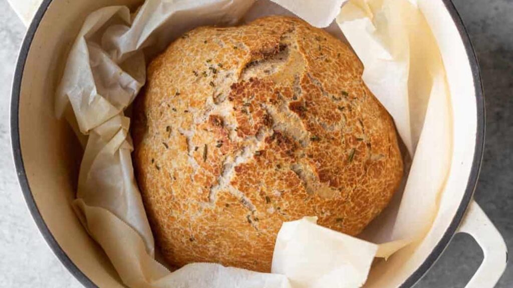 A loaf of bread in a parchment-lined dutch oven.