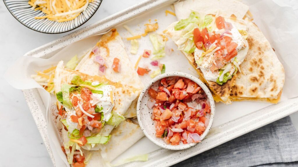 An overhead view of quesadilla on a tray with salsa.