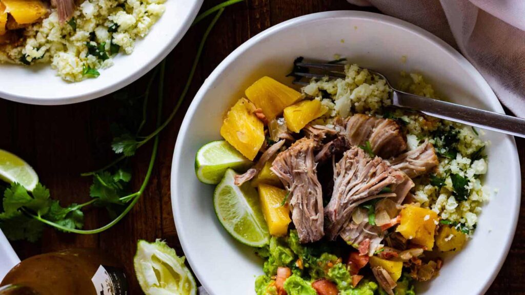An overhead view of two white bowls filled with slow cooker pineapple pulled pork.