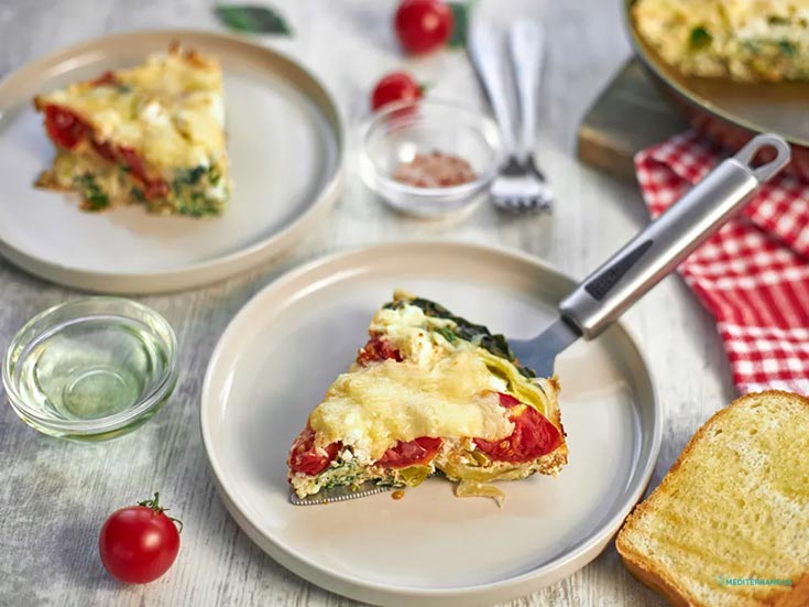 A slice of frittata sitting on a breakfast table.
