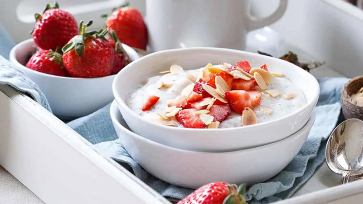 A whit bowl sits on a breakfast tray filled with strawberry coconut polenta.