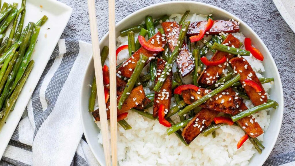 A white bowl filled with teriyaki tofu and white rice.