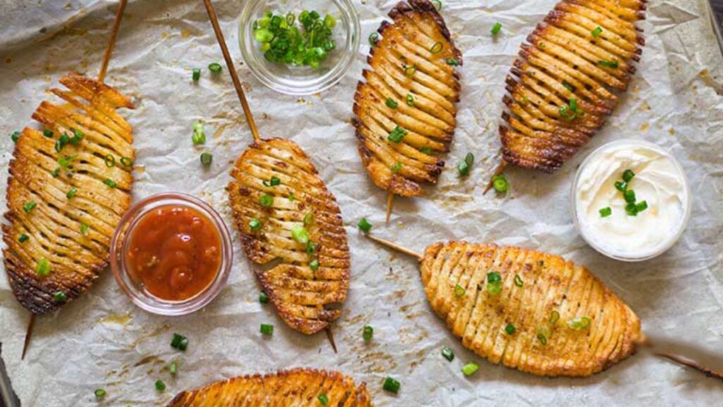 Accordion potatoes laying on parchment with small bowls of dip.