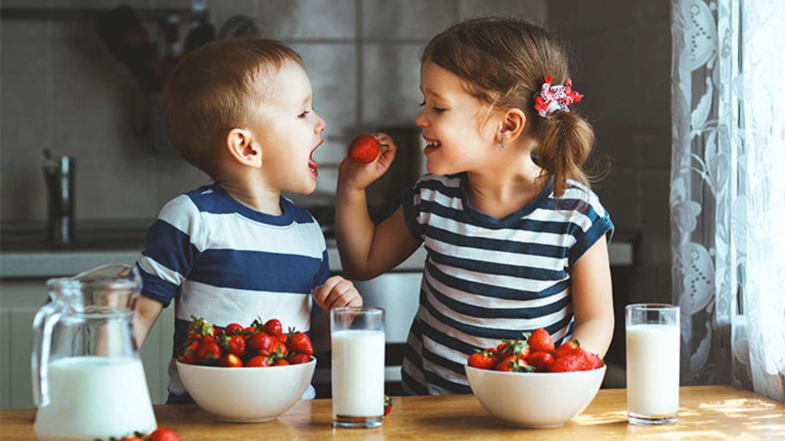 Two young kids eating strawberries.