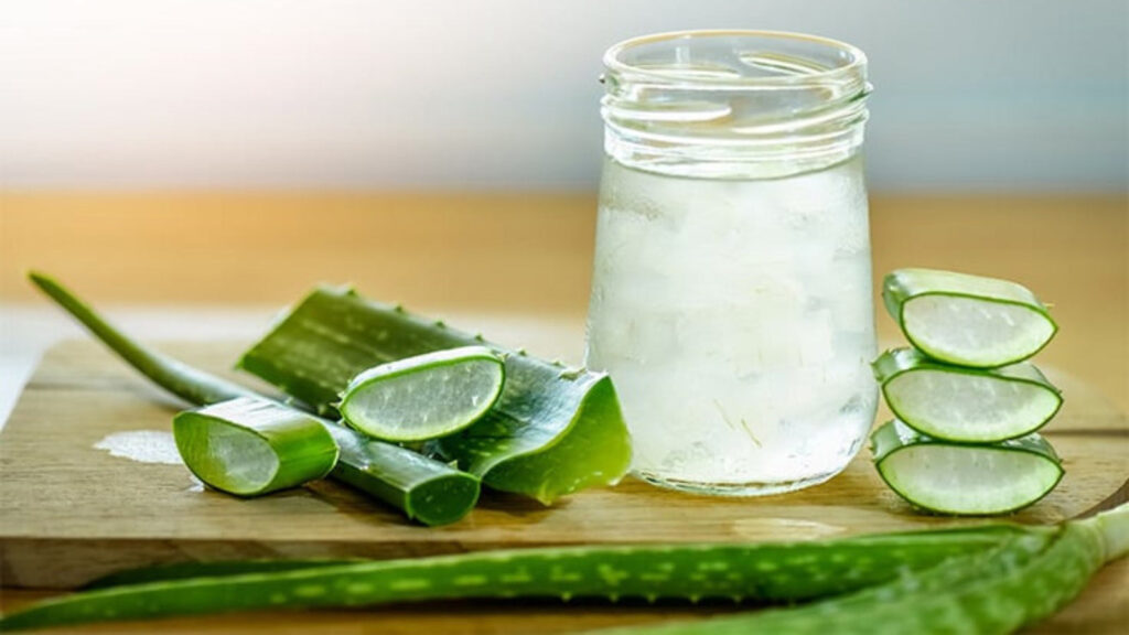Fresh aloe vera leaves and glass of aloe vera juice on wooden background