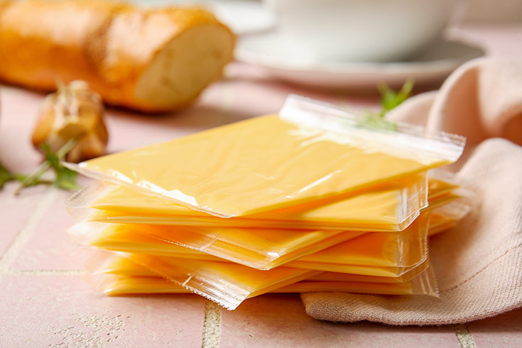 Slices of individually wrapped American cheese on a countertop.