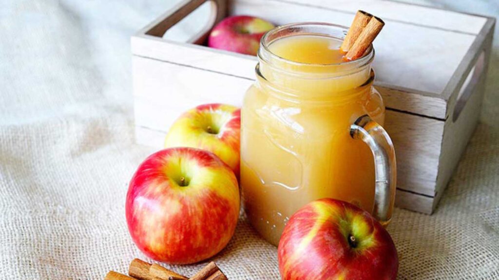 A side view of this hot apple cider recipe shows a full mug of cider with cinnamon sticks in the mug for stirring.