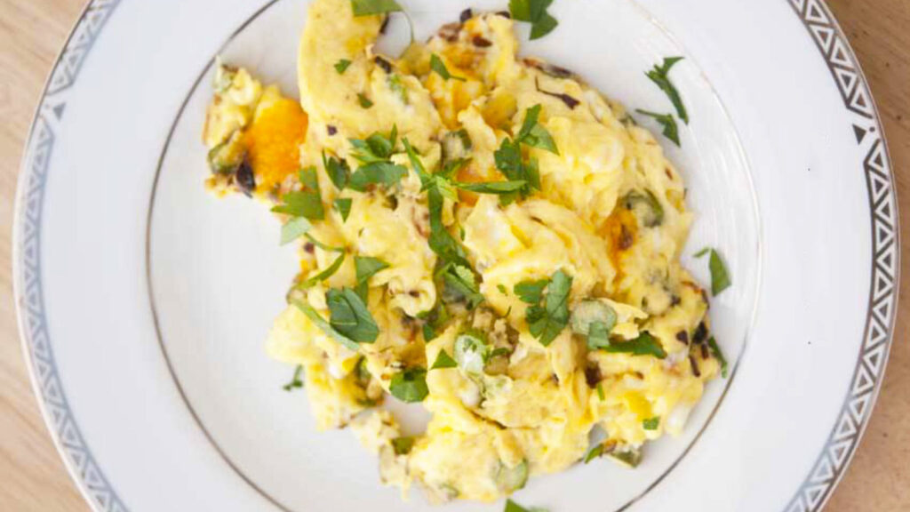 An Asparagus Cheddar Omelet on a white plate, garnished with fresh, chopped parsley.