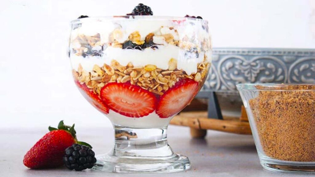 A Berry Trifle in a clear glass serving bowl with layers of berries, Greek yogurt, and whole-grain granola.
