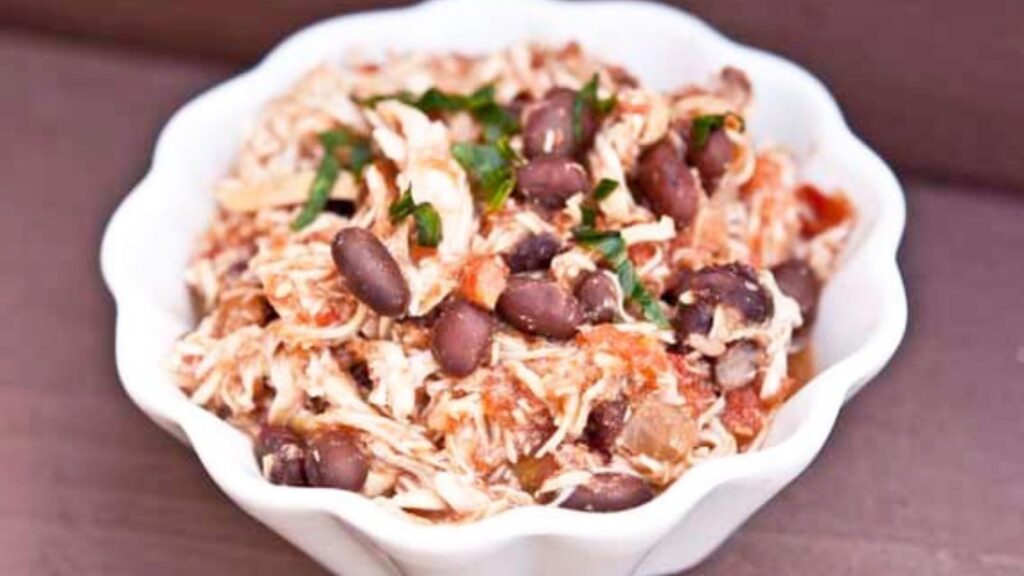 A white fluted bowl holds Mexican Chicken and Beans.