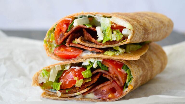 A finished BLT Wrap laying stacked on a piece of parchment.