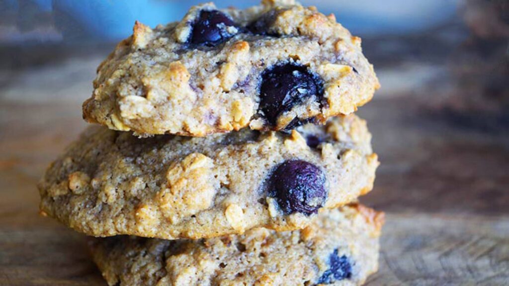 A stack of three Blueberry Breakfast Cookies on a cutting board.