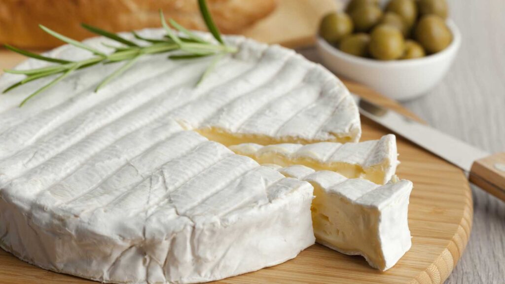A wheel of brie cheese with slices cut.