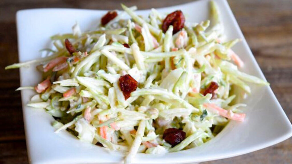 A white bowl filled with Broccoli Slaw.