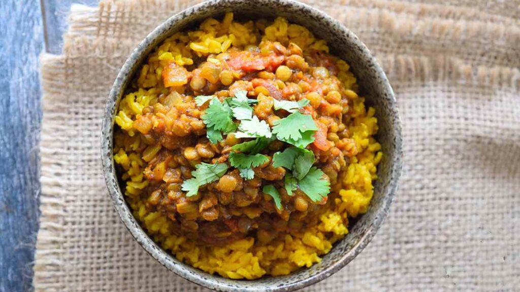 An overhead view of a bowl with lentil dal served over rice.