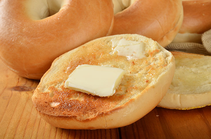 A cut and toasted bagel with a pat of butter on it.