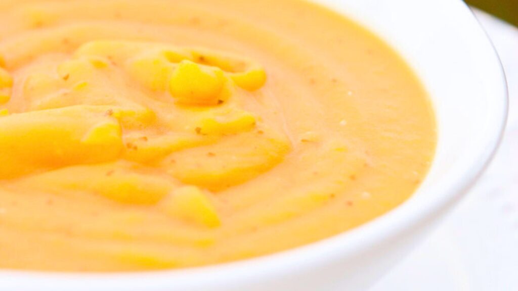 A white, ceramic bowl filled with butternut squash soup.