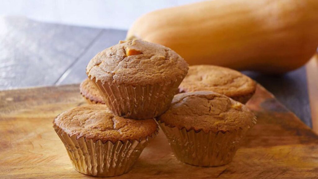 A side view of a stack of Butternut Squash Muffins on a cutting board.