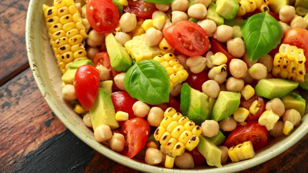 A bowl of Cajun corn salad on a wood surface.