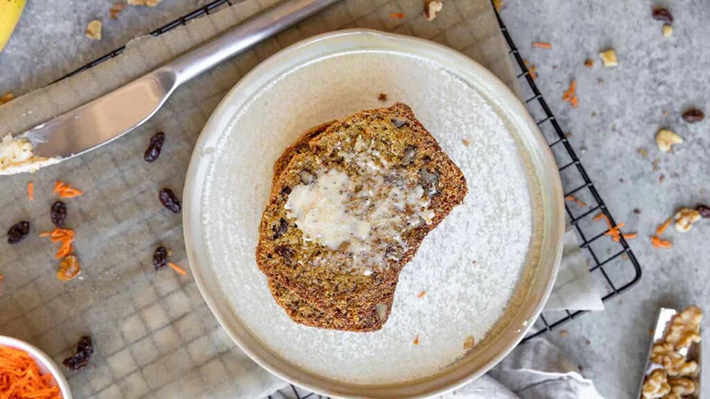 Carrot cake banana bread slices with butter on a plate.