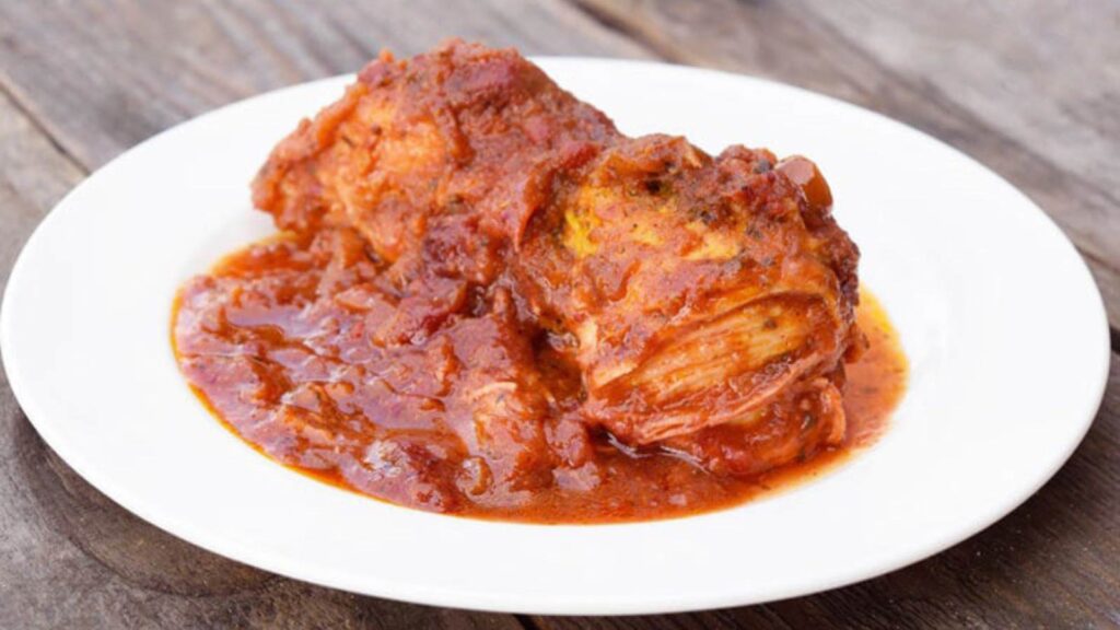 A chicken breast covered in Catalina cranberry sauce, on a white plate.