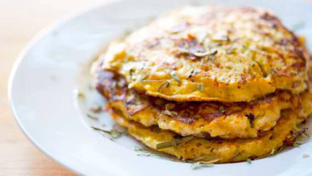 A white plate holding a stack of cauliflower fritters.