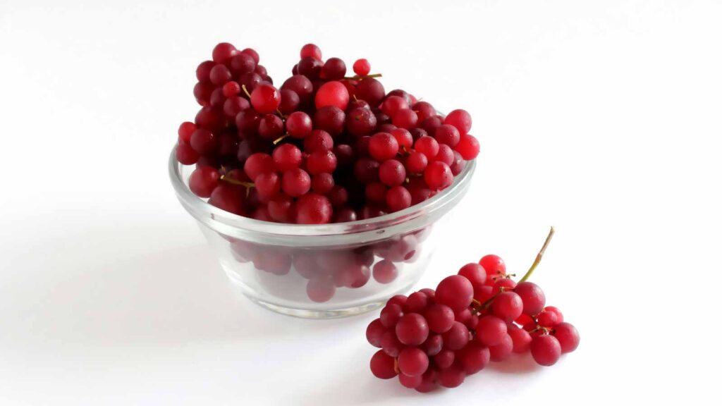 Champagne Grapes also known as Black Corinth or Zante Currant in a bowl with white background.