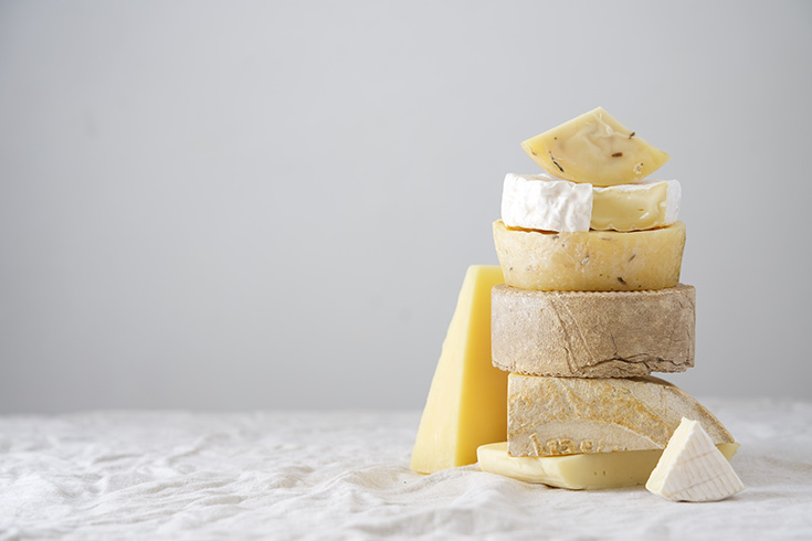 A stack of various cheeses on a white table.