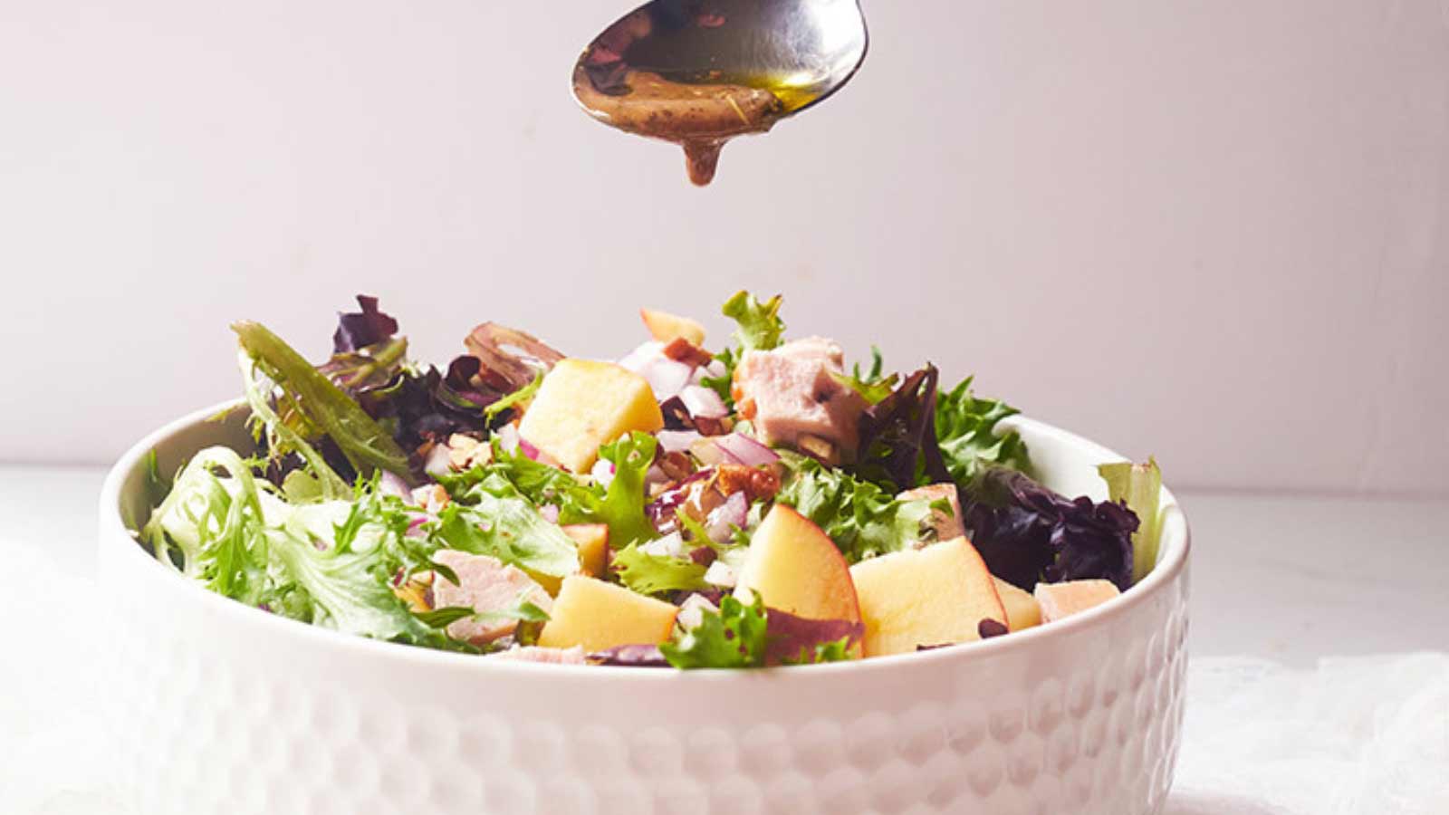 The finished Chicken Apple Salad having dressing spooned over the top.