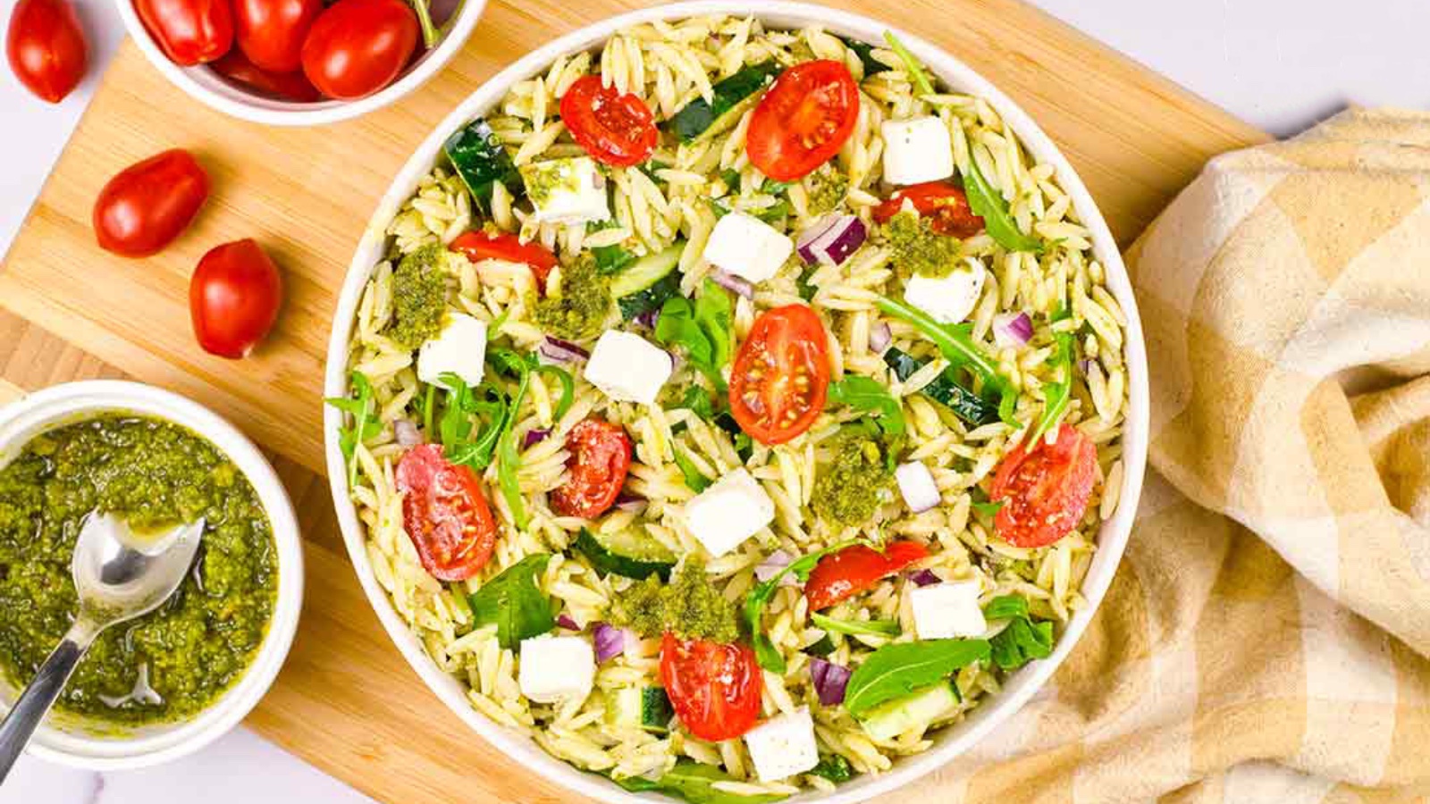 An overhead view of a white bowl filled with orzo pasta with pesto sacue.