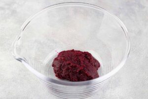 Beet puree in a clear, glass bowl.
