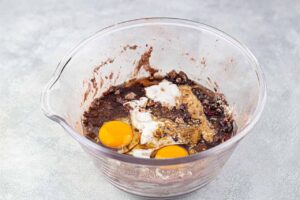 Eggs and wet ingredients added to dry ingredient in a mixing bowl.