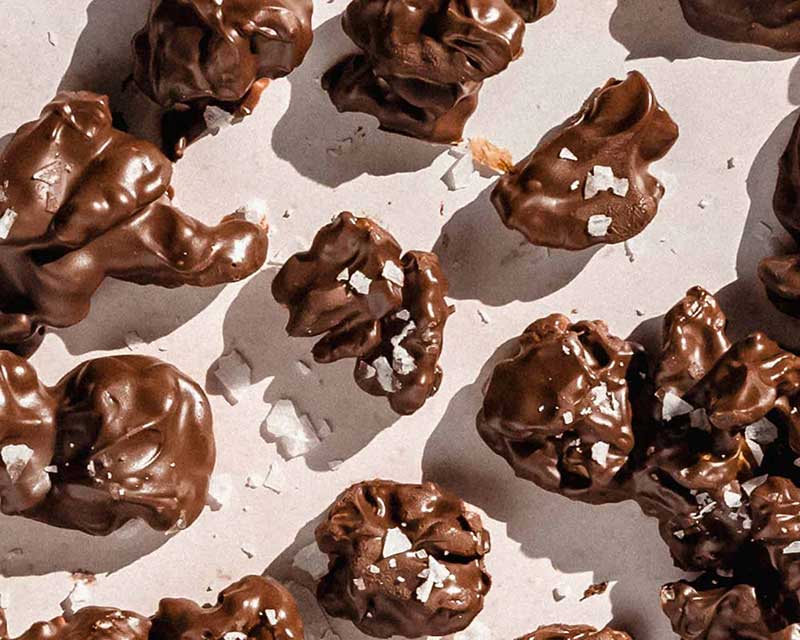 Nuggets of chocolate covered walnuts on a white surface.