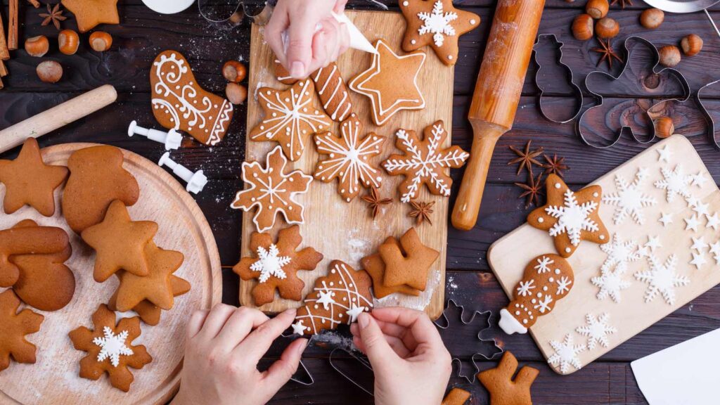 An overhead view of people working on decorating holiday cookies.