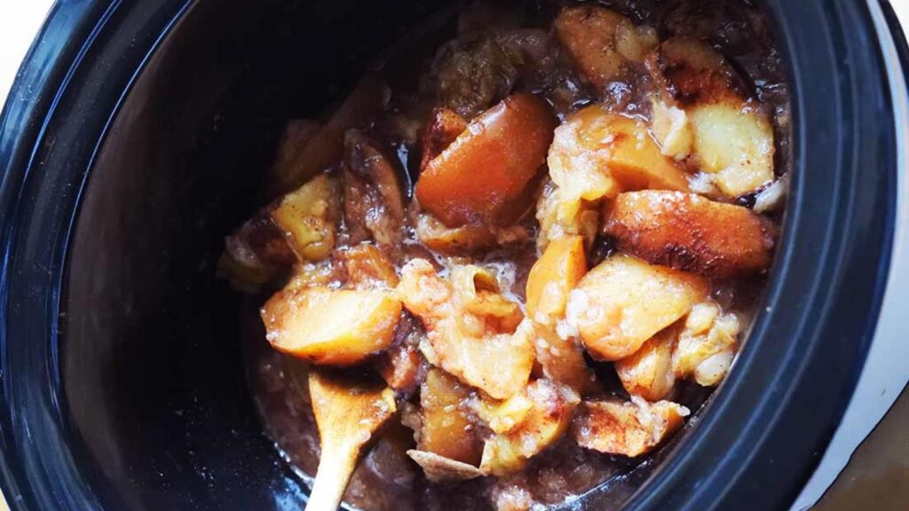 A slow cooker half full with Crockpot Cinnamon Apples.